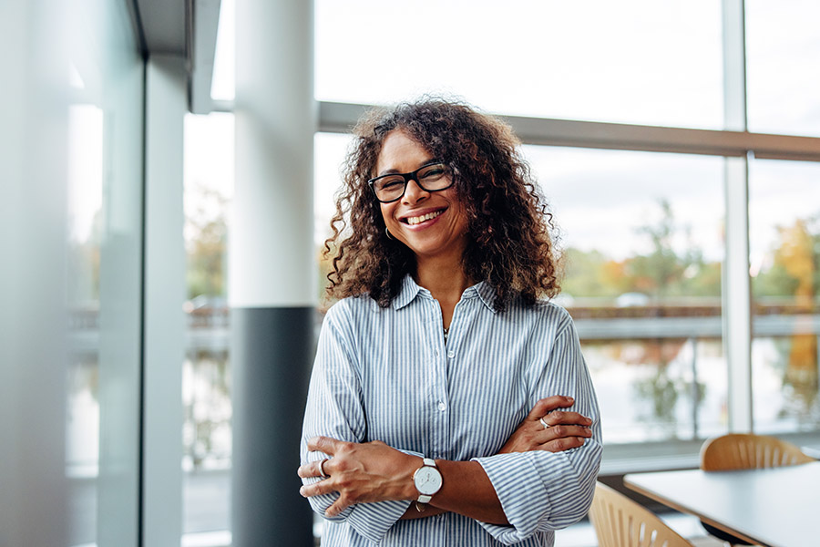 HR Support and Online Enrollment - Closeup Portrait of a Smiling Mature Business Woman with Glasses Standing in a Modern Office